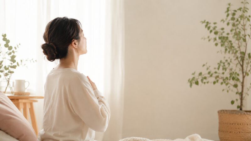 朝の静かな部屋で深呼吸をしながら瞑想する女性